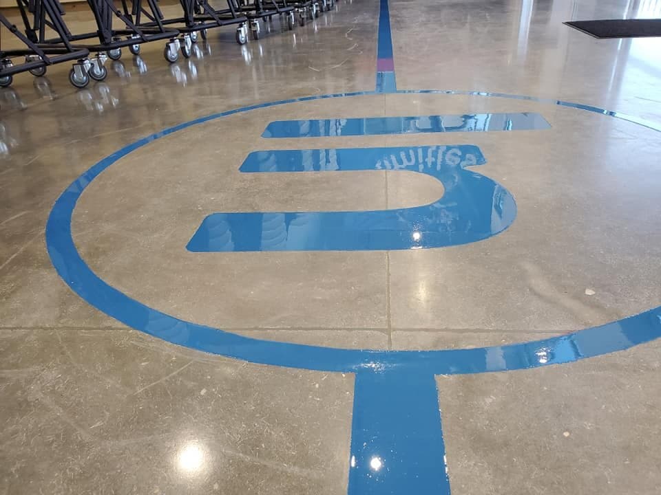 Corporate logo engraved into a polished concrete floor and filled with glossy epoxy