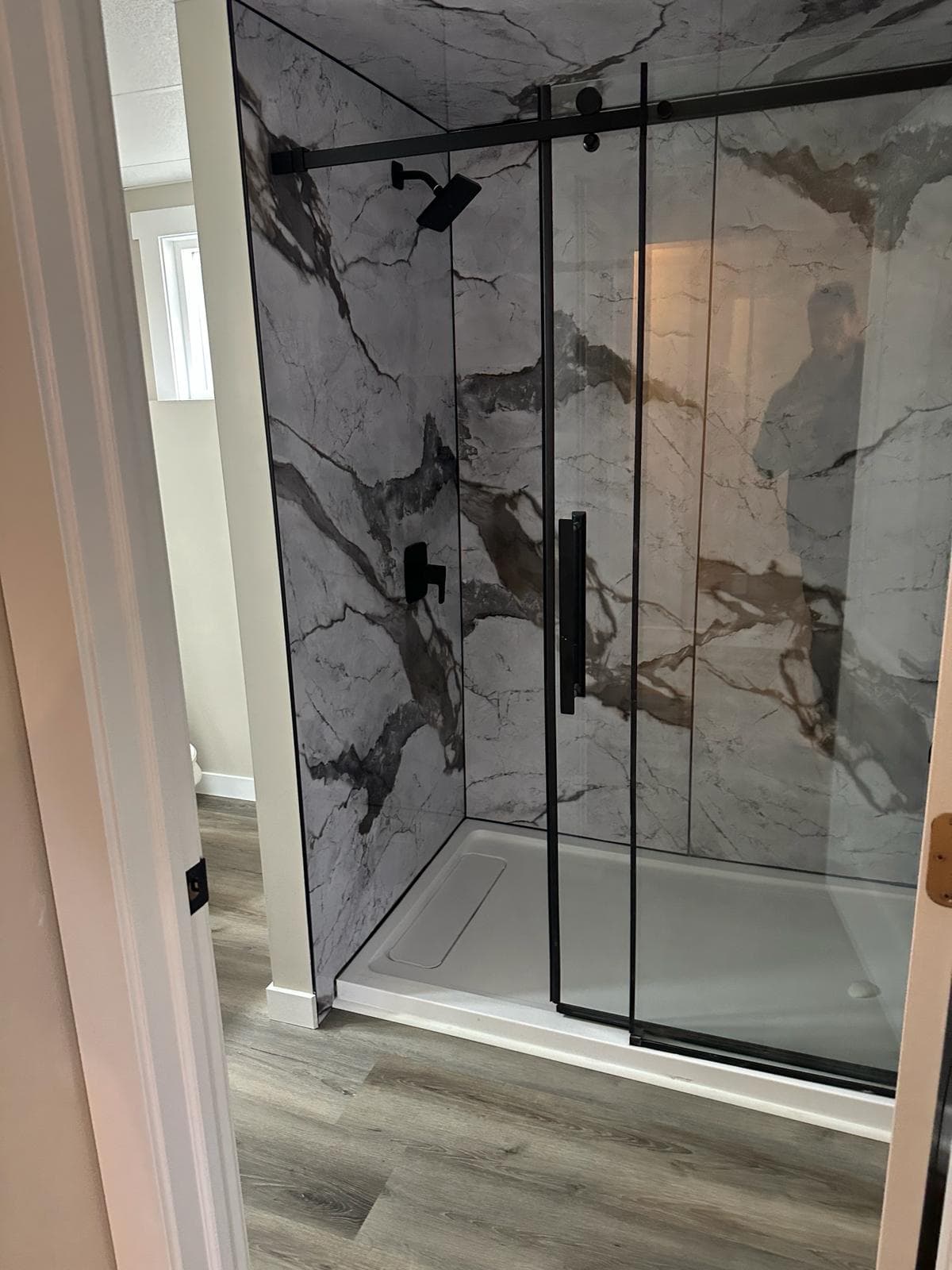 Bathroom with marble walk-in shower and black hardware — JFK Surfaces renovation in Central Alberta